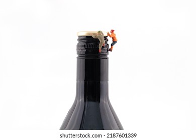 Miniature scene climbing wine bottle to drink