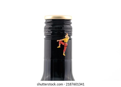 Miniature scene climbing wine bottle to drink