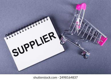 Miniature Shopping Cart Tipped Over Next to Notepad With Word SUPPLIER on Grey Background - Powered by Shutterstock