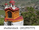 Miniature shrine of painted cement in the shape of a Byzantine-style Orthodox church, viewpoint on the dirt road climbing up from the town to Leusa village and the Saint Mary