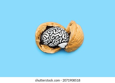 Miniature steel brain in a walnut shell isolated on blue background. Brain food essentials concept.