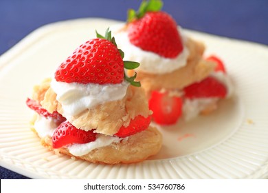 Miniature strawberry shortcakes with whipped cream and fresh berries on a white dish