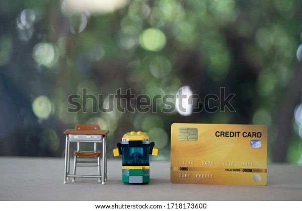 Miniature student table and school bus with\
credit card on wood table. Concept of pay fees for general\
education or elementary\
education