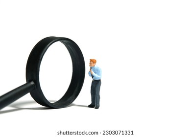 Miniature tiny people toy figure photography. A businessman getting ready, justify the tie beside magnifier glass. Isolated on white background. Image photo