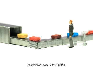 Miniature tiny people toy figure photography. A businessman standing waiting for his baggage at the airport. Isolated on a white background. Image photo