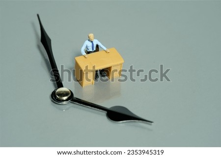 Miniature tiny people toy figure photography. Waiting concept. A businessmen seat on his desk with clockwise. Isolated on a grey background. Image photo