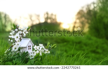 miniature toy house in grass close up, spring natural background. ymbol of family. mortgage, construction, rental, property concept. Eco Friendly home. spring season. template for design. copy space