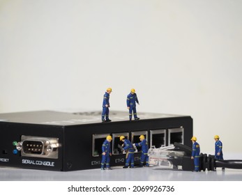 Miniature toys with black ethernet cable and blurred black router hardware on the white background. Computer network business concept. - Shutterstock ID 2069926736