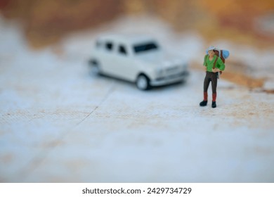 A miniature traveler with a backpack standing next to a classic car model on a vintage map background.
 - Powered by Shutterstock