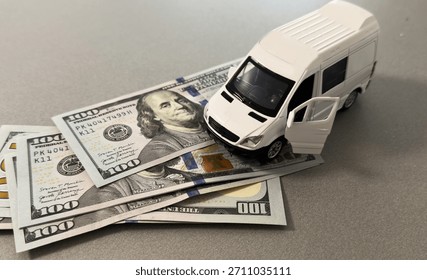  Miniature van on stack of dollar bills, symbolizing saving and financial planning for future travel.
