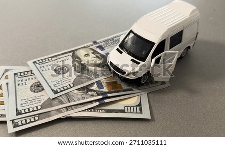  Miniature van on stack of dollar bills, symbolizing saving and financial planning for future travel.