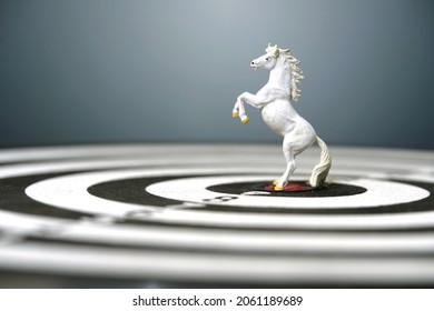 Miniature of white prancing horse standing in the center of dartboard isolated on grey background. Image photo