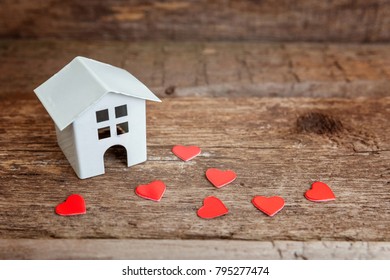 Miniature white toy house with red hearts on a wooden table. Mortgage property insurance dream home concept