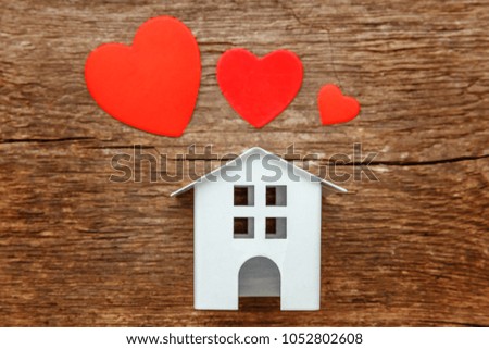 Miniature white toy house with red hearts on a rustic old vintage wooden background. Mortgage property insurance dream home concept
