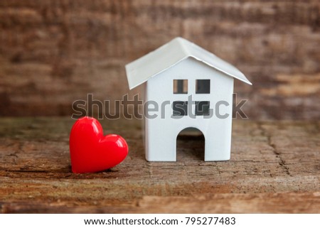 Miniature white toy house with red heart on a wooden table. Mortgage property insurance dream home concept
