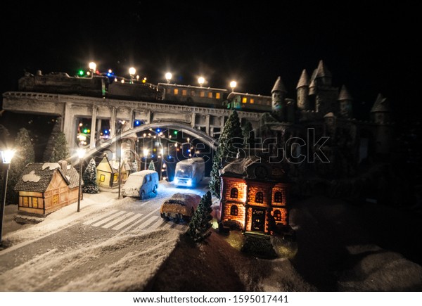 Miniature of winter snowy scene with train on\
bridge, medieval castle and small city. Holiday attributes. Night\
scene. New Year and Christmas concept. Creative artwork mini on\
table decoration