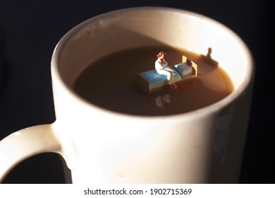 Miniature woman on a bed in a cup of coffee. Waking up with caffeine to start day. Time to start your morning with a hot cup of java. Coffee is a big part of our day.  Insomnia or exhaustion concept. 