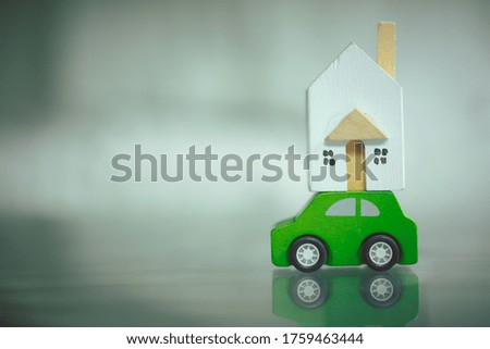 Miniature wood home on green toy car. House moving and real estate concept