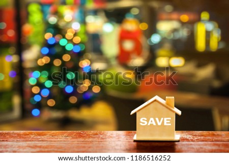 miniature wood house on wooden mock up over blurred Christmas decoration background.Image for property real estate investment concept. 