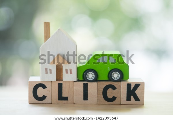 Miniature wooden home and wooden car on wood\
block with words \