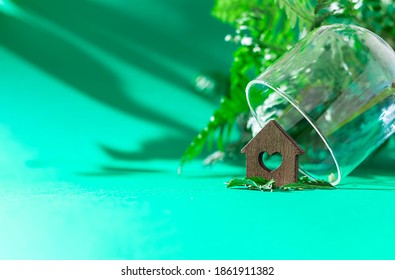 Miniature Wooden House In Glass Dome On Green Background. Dream House Concept, Real Estate Investment. Property Insurance. Selective Focus