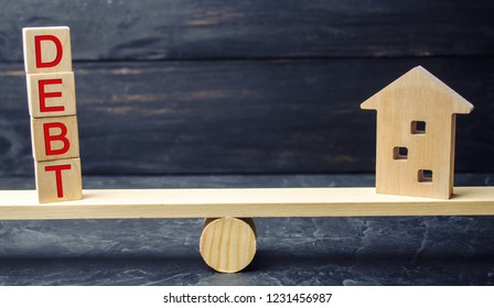 Miniature Wooden House And The Inscription Debt. Real Estate, Home Savings, Loans Market Concept. Payment Of Real Estate Tax. Mortgage. Risks Of Buying A House. Foreclosure