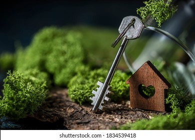 Miniature wooden house with a key on the background of nature. Dream house concept, real estate investment. Buying a new family home in an ecologically clean place. Selective focus