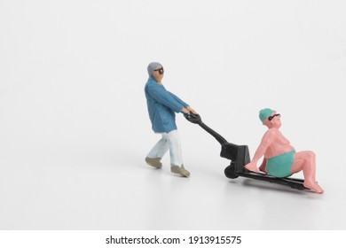 Miniature Of A Worker Carrying A Fat Man With Bathing Suit