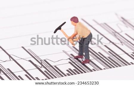 Miniature worker with pickaxe working on a graph