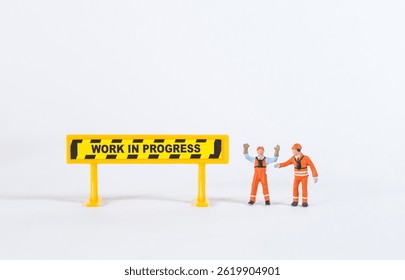 Miniature worker with work in progress sign isolate on white background, construction industry concept