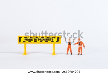 Miniature worker with work in progress sign isolate on white background, construction industry concept