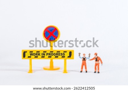 Miniature worker with work in progress sign isolate on white background, construction industry concept