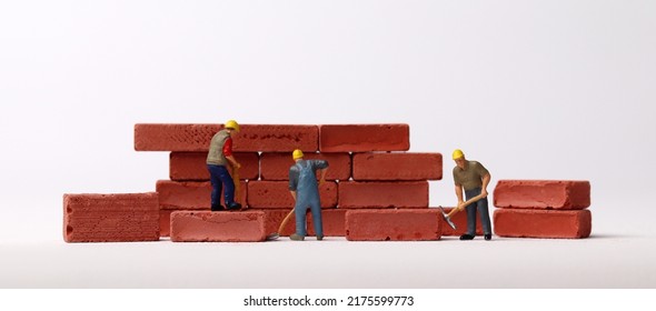 Miniature Workers Building Bricks. Business Concept With Bricks And Miniature People.