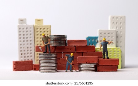 Miniature workers building bricks. Business concept with coins and miniature people. - Powered by Shutterstock