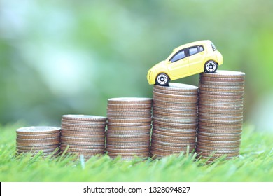 Miniature yellow car model on growing stack of coins money on nature green background, Saving money for car, Finance and car loan, Investment and business concept 