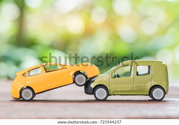 Miniature yellow and green car crashed over\
green background,car insurance\
concept.
