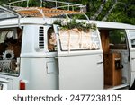 A minibus or van converted into a photo booth is seen at a summer wedding reception. The word photos is lit up on an LED sign.