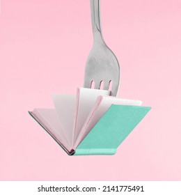 Minimal Abstract Art Concept Made Of Fork And Green Book On Isolated Pastel Pink Background With Copy Space. The Idea Of Book Fair, Reading, Promotions Or Education. Poster, Wallpaper Or Gift Card.