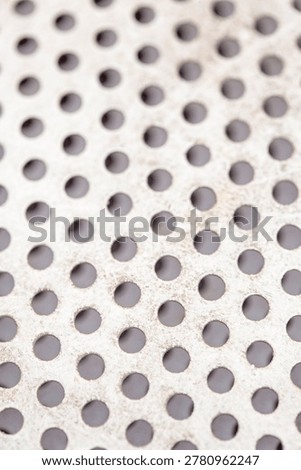 Minimal abstract background featuring white perforated metal with repeating circular holes and subtle distressed texture. Clean industrial design with geometric appeal.