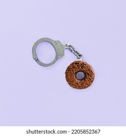 Minimal Abstract Scene With Chocolate Donut As A Part Of Handcuffs On Isolated Pastel Purple Background. Concept Of Sugar Addiction, Craving For Sweets Or  Eating Carbs Food. Flat Lay.