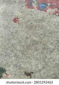 A minimal abstract texture featuring a worn concrete surface with scattered patches of faded red, green, and blue paint. The aged, weathered background creates a rustic and distressed appearance, perfect for grunge designs, artistic backdrops, and vintage texture projects.