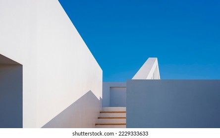 Minimal Architecture Modern House. White Concrete Building Structure with Light and Shadow on surface of Steps to Rooftop against Blue Sky Background, low angle view with copy space - Powered by Shutterstock