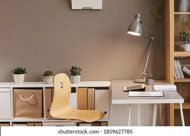 Minimal background image of cozy workplace lit by warm lighting from metal desk lamp, copy space