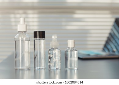 Minimal Background Image Of Various Hand Sanitizers On Empty Workplace Desk In Post Pandemic Office, Copy Space