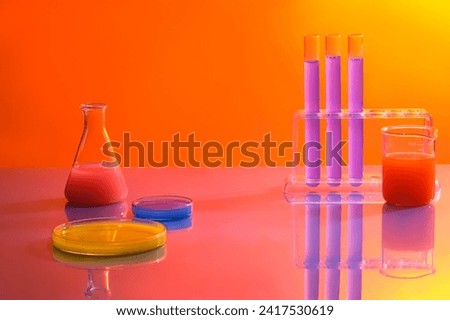 Minimal background with lab concept. Test tubes, beaker, erlenmeyer flask and petri dishes filled with colorful solution on orange gradient background. Space for cosmetics and product presentation
