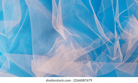 A minimal background made of pastel pink tulle wrapped on blue background. Elegant design. Flat lay. Copy space.