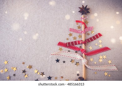 Minimal Christmas tree made from reusable ribbons, eco straw and anise star, fairy light and toning background