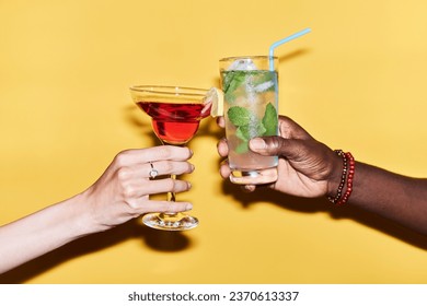 Minimal close up of multiethnic couple clinking cocktails against vibrant yellow background - Powered by Shutterstock