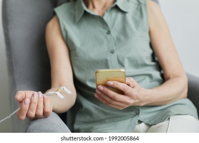 Minimal close up of unrecognizable woman getting IV drip and using smartphone, copy space
