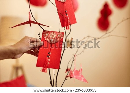 Minimal closeup of female hand holding hongbao red envelope as Chinese New Year tradition, copy space Translation Have overflowing abundance hundred years